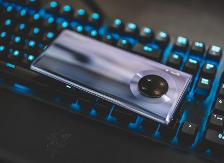 编辑在笔记本上逐条比对公开信源与截图证据，屏幕泛着宝石蓝紫光，氛围专注克制